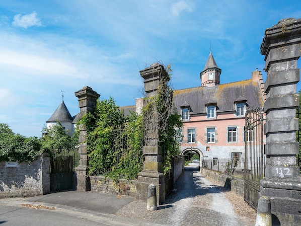 A historic building with a stone gate, a tower, and a paved pathway leading to the entrance.