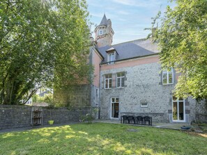 A stone building with a tower, a grassy yard, and a metal chair table.