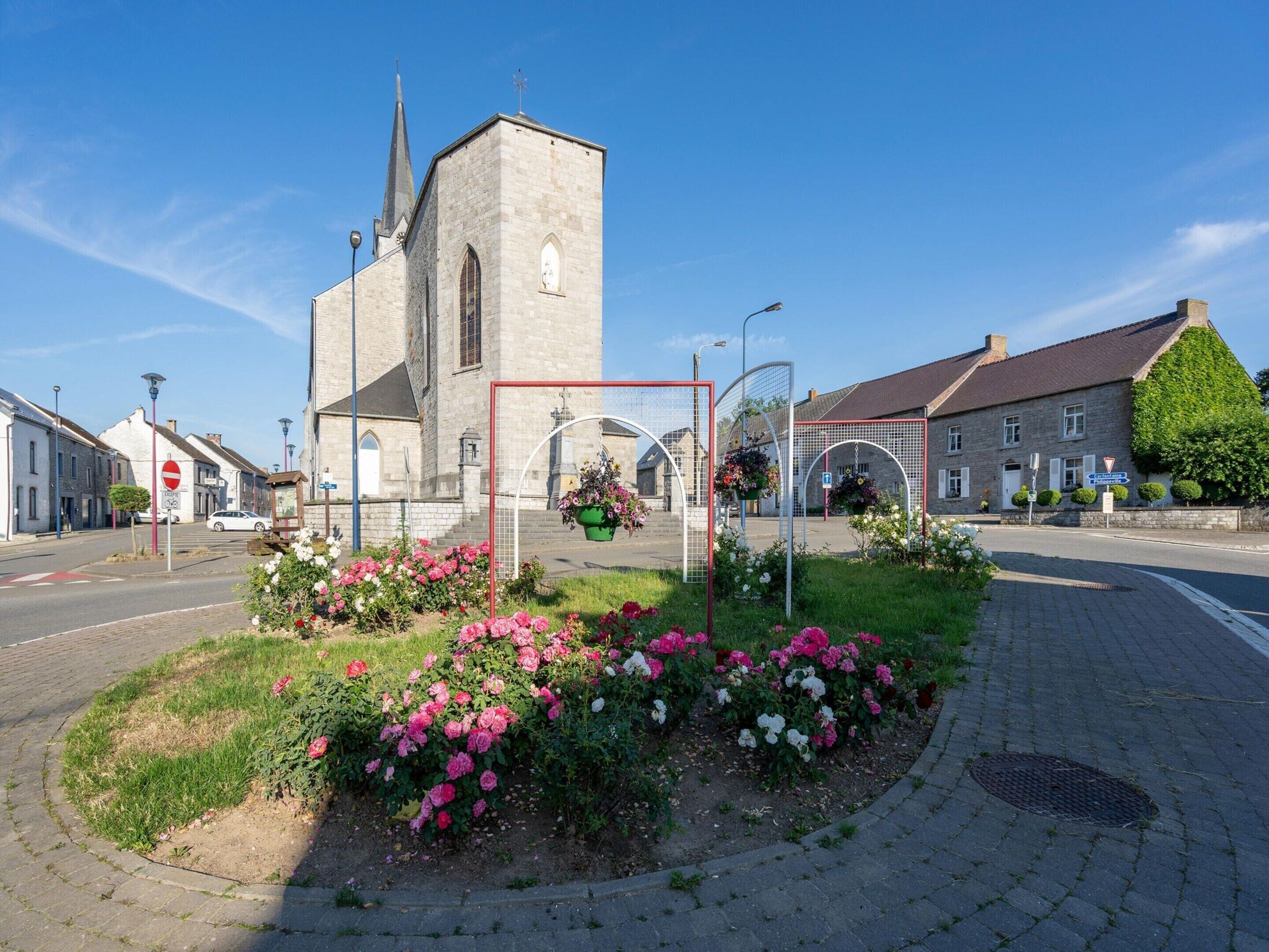 Uma igreja com um campanário alto, um jardim de flores com rosas e uma faixa de pedestres.