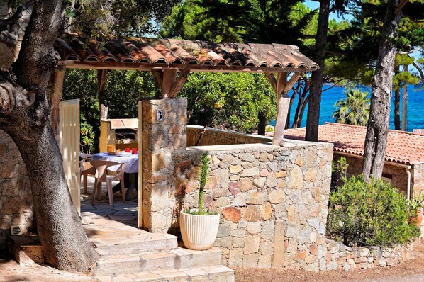 Un patio de piedra con mobiliario exterior, una pérgola y vistas al mar.