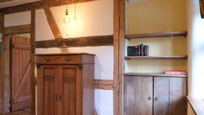 A rustic room with exposed wooden beams, a wooden cabinet, and a bookshelf with books. - Peaceful Escape in Neu Karin (Carinerland)