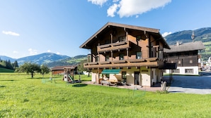 A traditional wooden chalet with a balcony, surrounded by a lush green field and mountains in the background. - Chalet in Mittersill Near Ski Slopes (Mittersill)