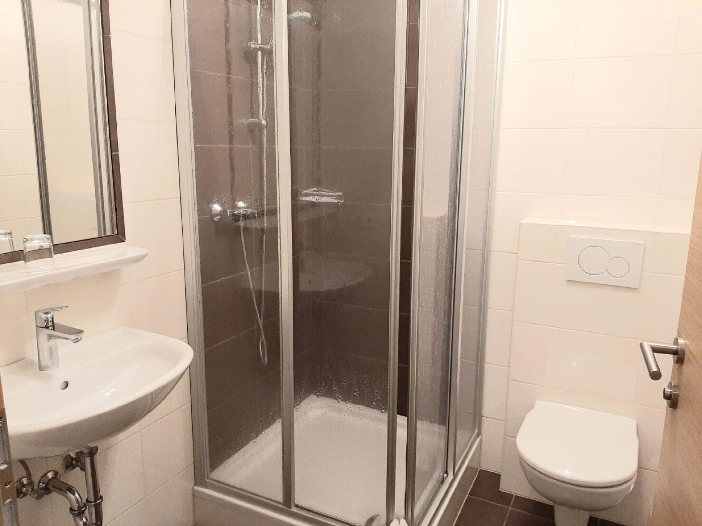 Ein Badezimmer mit Duschkabine, Waschbecken und Toilette.