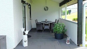 A covered patio with a table and chairs, a potted plant, and a decorative item. - Holiday Home in Gonnersdorf With Sauna (Gonnersdorf)