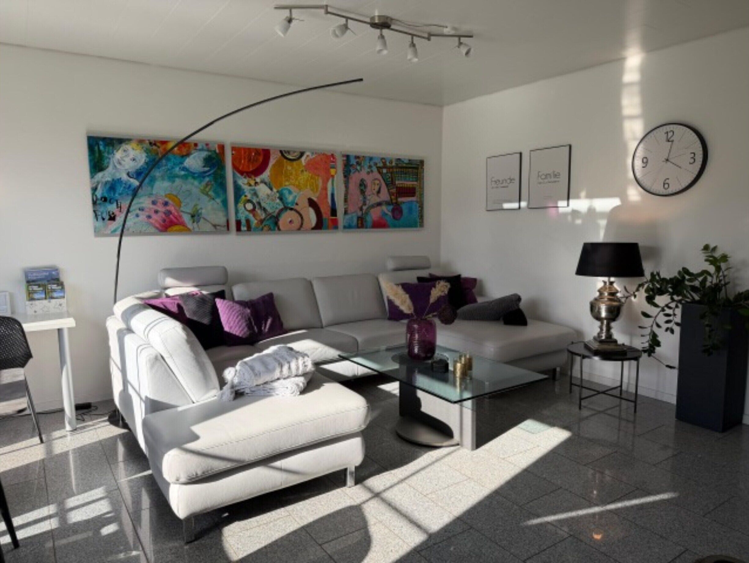 A modern living room with a sofa, coffee table, and artwork on the wall.