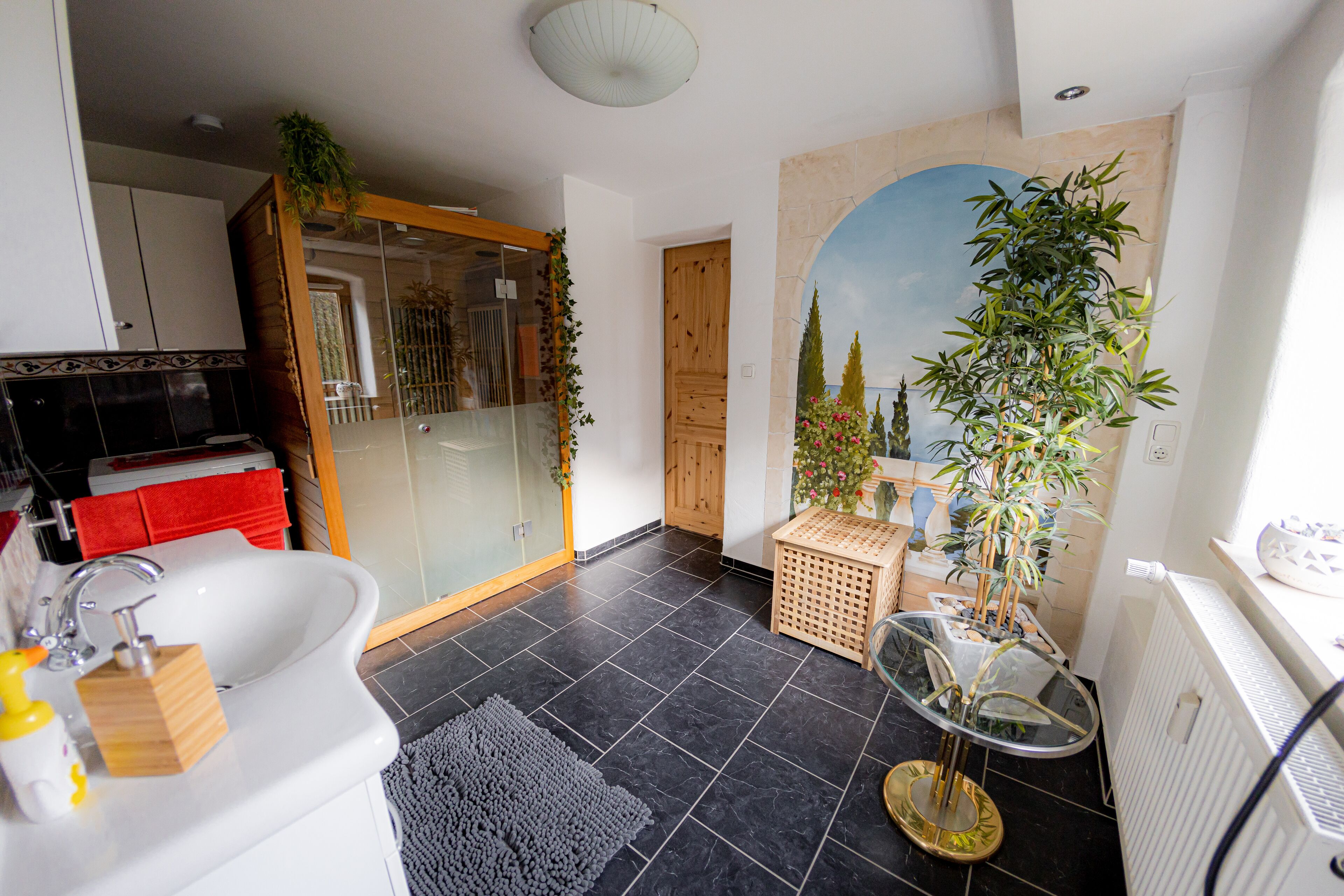 A modern bathroom with a white sink, a glass shower enclosure, and a large mirror.