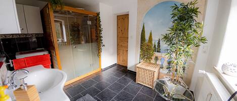 A modern bathroom with a white sink, a glass shower enclosure, and a large mirror.