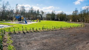 A playground with slides and climbing structures, surrounded by a grassy area and trees. - Nice Holiday Home in Appelscha With Garden (Appelscha)