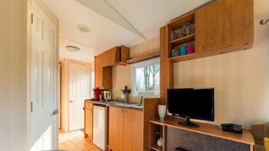 A compact kitchen with wooden cabinets, a built-in stove, and a window overlooking a forest. - Nice Holiday Home in Appelscha With Garden (Appelscha)