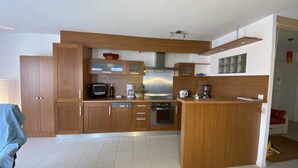 A modern kitchen with wooden cabinets, a microwave, a coffee maker, and a stove.