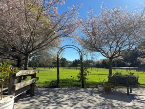 A park with cherry blossoms, a wooden bench, and a metal archway. - Newfields Country Retreat - incl bfst (Sefton)