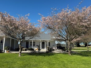 A house with a covered porch, a lawn, and cherry blossom trees. - Newfields Country Retreat - incl bfst (Sefton)