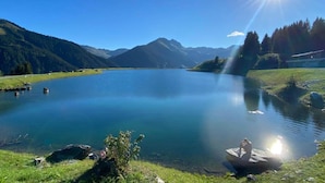 A serene lake with mountains in the background, a clear sky, and a person sitting on a dock. - Comfortable Holiday Home in Kleinarl (Kleinarl)