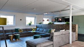 Una sala de estar moderna con un sofá modular, una mesa de centro y un comedor con cocina al fondo.
