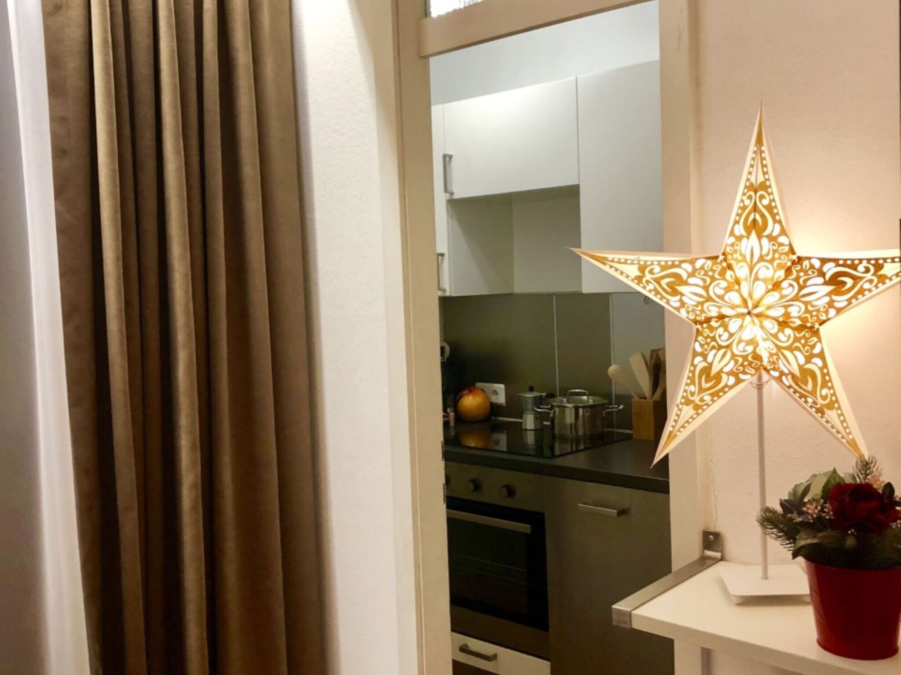 A kitchen with stainless steel appliances, a white cabinet, and a decorative star-shaped light fixture.