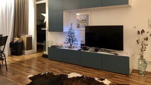 Ett modernt vardagsrum med en inbyggd TV, ett litet julgran och en matta av kohud.