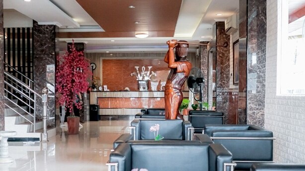 A hotel lobby with a reception desk, a statue, and seating areas. - WINER HOTEL PALEMBANG (Palembang)