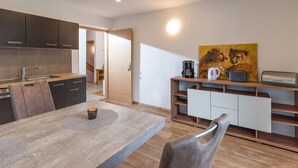 Una cocina moderna con armarios oscuros, una mesa de comedor de madera y un cuadro de chitas en la pared.