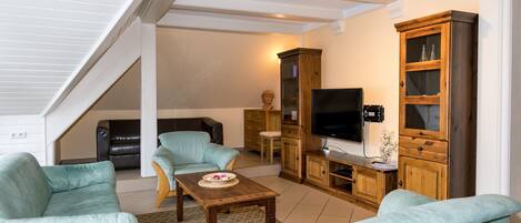 A living room with a TV, wooden cabinet, and two sofas.