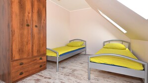 A small room with two metal beds, a wooden wardrobe, and a slanted ceiling with skylight. - Seaside Cottage With Terrace and Lovely Garden (Darlowo)