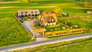 A rural property with a large barn, a smaller house, and a fenced garden area. - Seaside Cottage With Terrace and Lovely Garden (Darlowo)