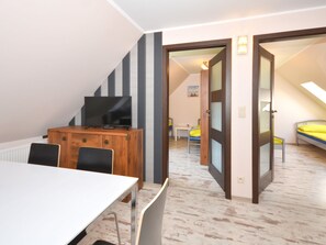 A room with a bed, a TV on a wooden cabinet, a dining table, and a chair.