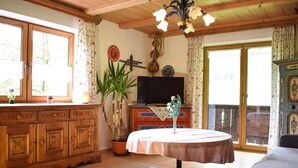 Una habitación acogedora con techo de madera, un ventanal grande, televisor, una mesa de comedor y un sofá.