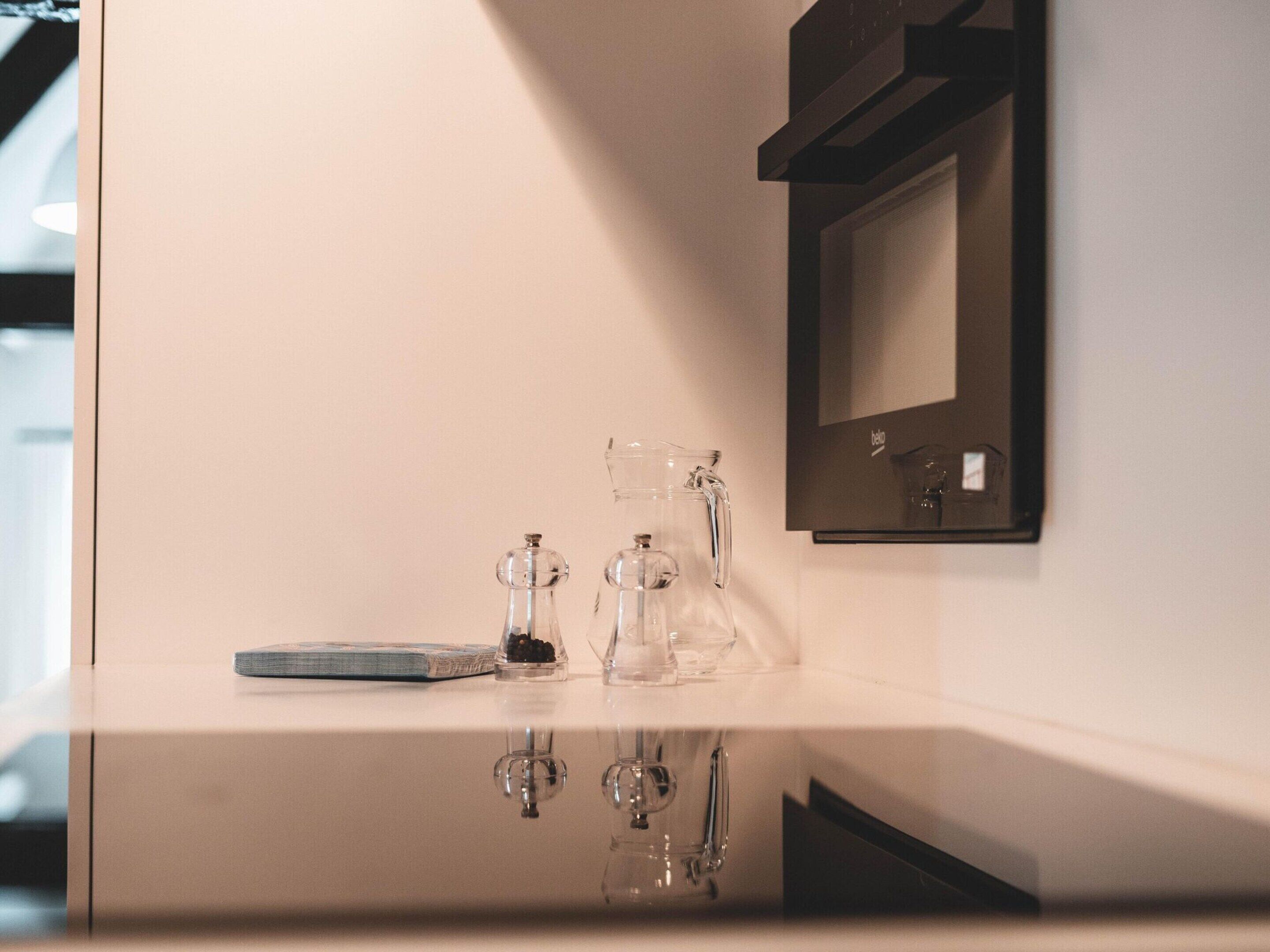 A bathroom with a mirror, a sink, and a glass pitcher.