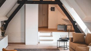En moderne loftlejlighed med trappe op til et højere niveau, en sofa, et sofabord og et lille sofabord.