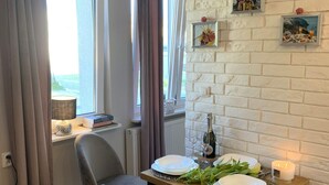 A dining area with a table set for two, a chair, a bottle of wine, and a candle. - Apartment in Gdynia Near Baltic Beach (Gdańsk)