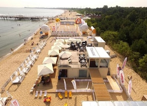 A beachside hotel with outdoor seating, umbrellas, and a view of the sea. - Apartment in Gdynia Near Baltic Beach (Gdańsk)