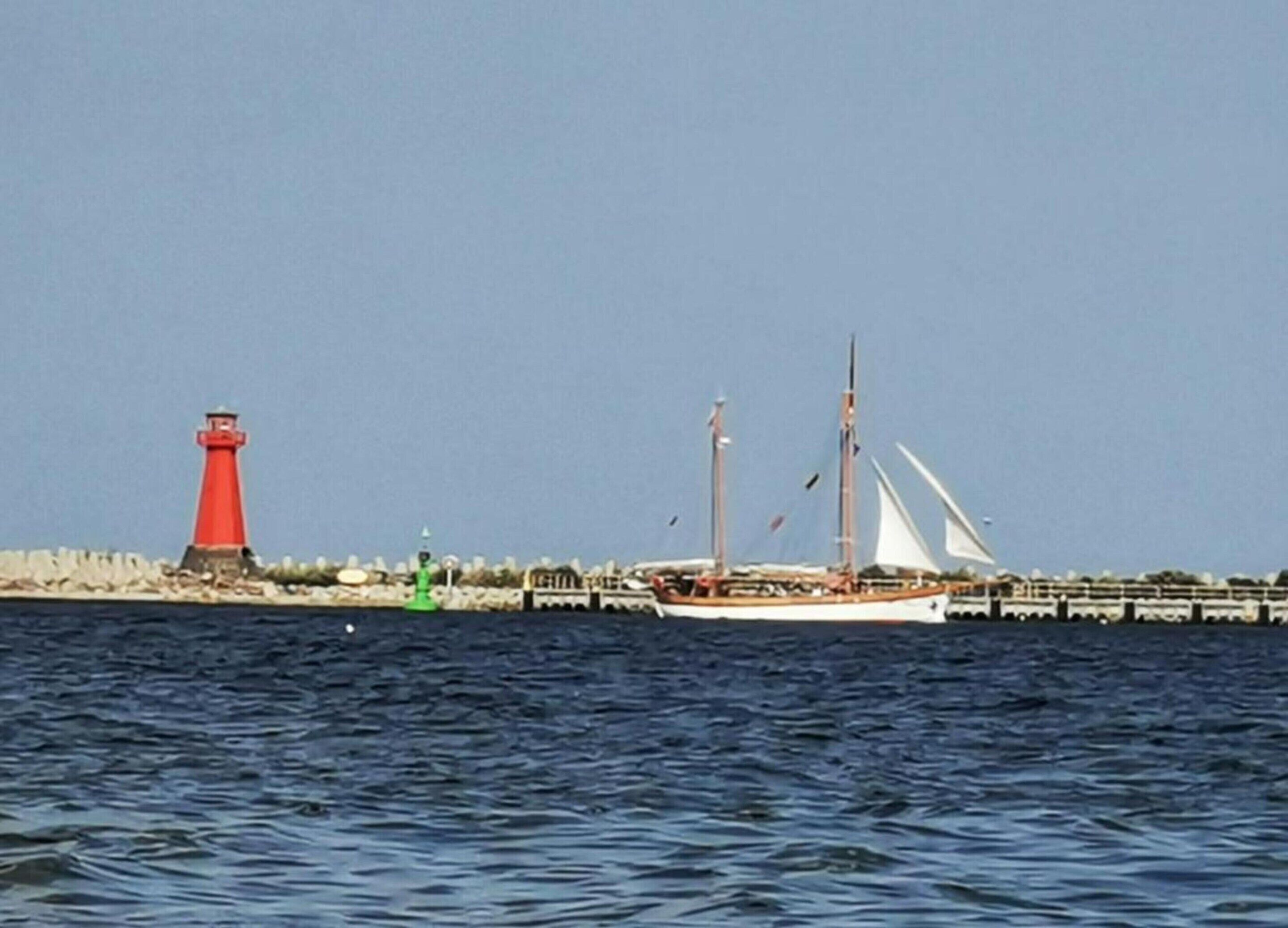 Un faro y un velero en aguas tranquilas.