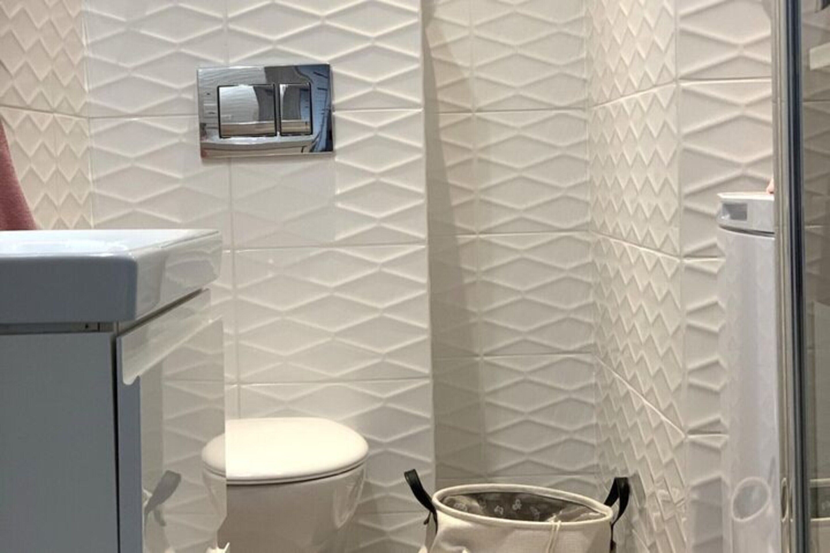 A modern bathroom with a white toilet, a bidet, and a glass shower enclosure.