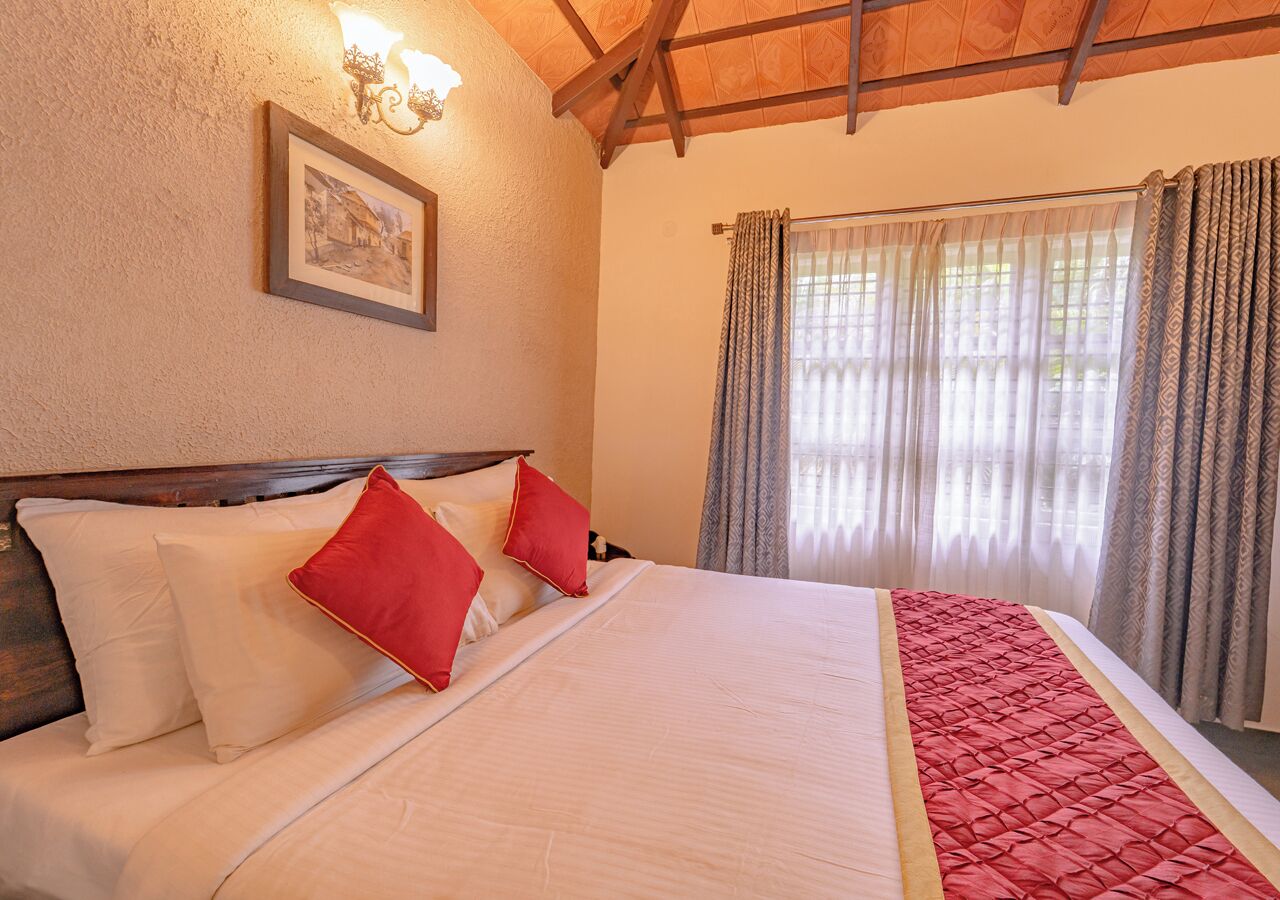 Habitación de hotel con una cama grande, cabecera de madera, un cuadro enmarcado en la pared y una ventana con cortinas.