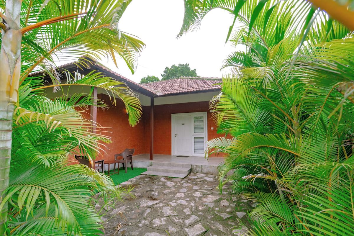A building with a tiled roof, a door, and a small outdoor seating area with chairs.