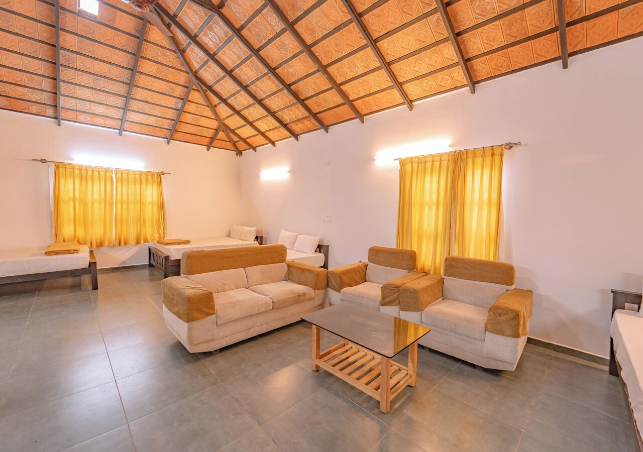 A spacious living room with a high ceiling, two sofas, a coffee table, and yellow curtains.