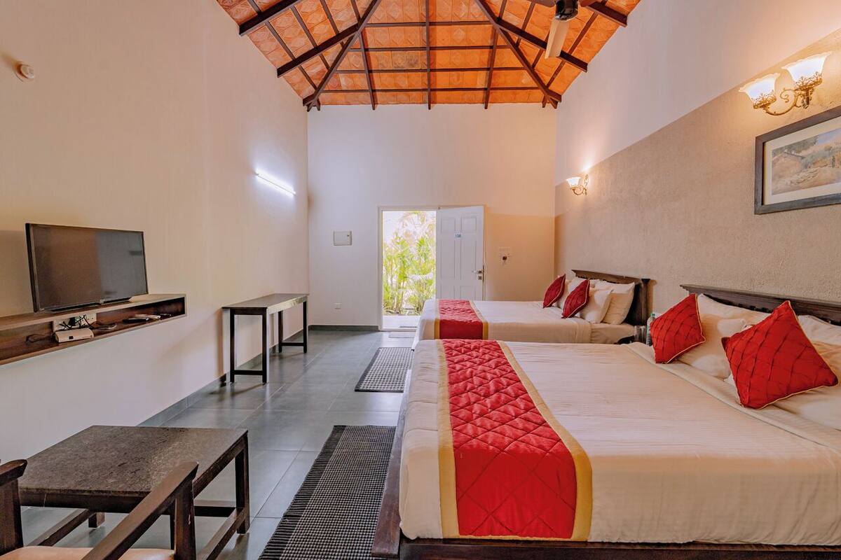 A hotel room with two beds, a TV, a desk, and a view of the outdoors.