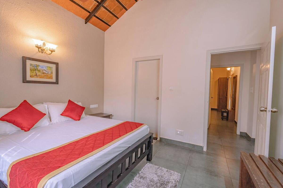 A bedroom with a bed, a door, and a hallway leading to another room.