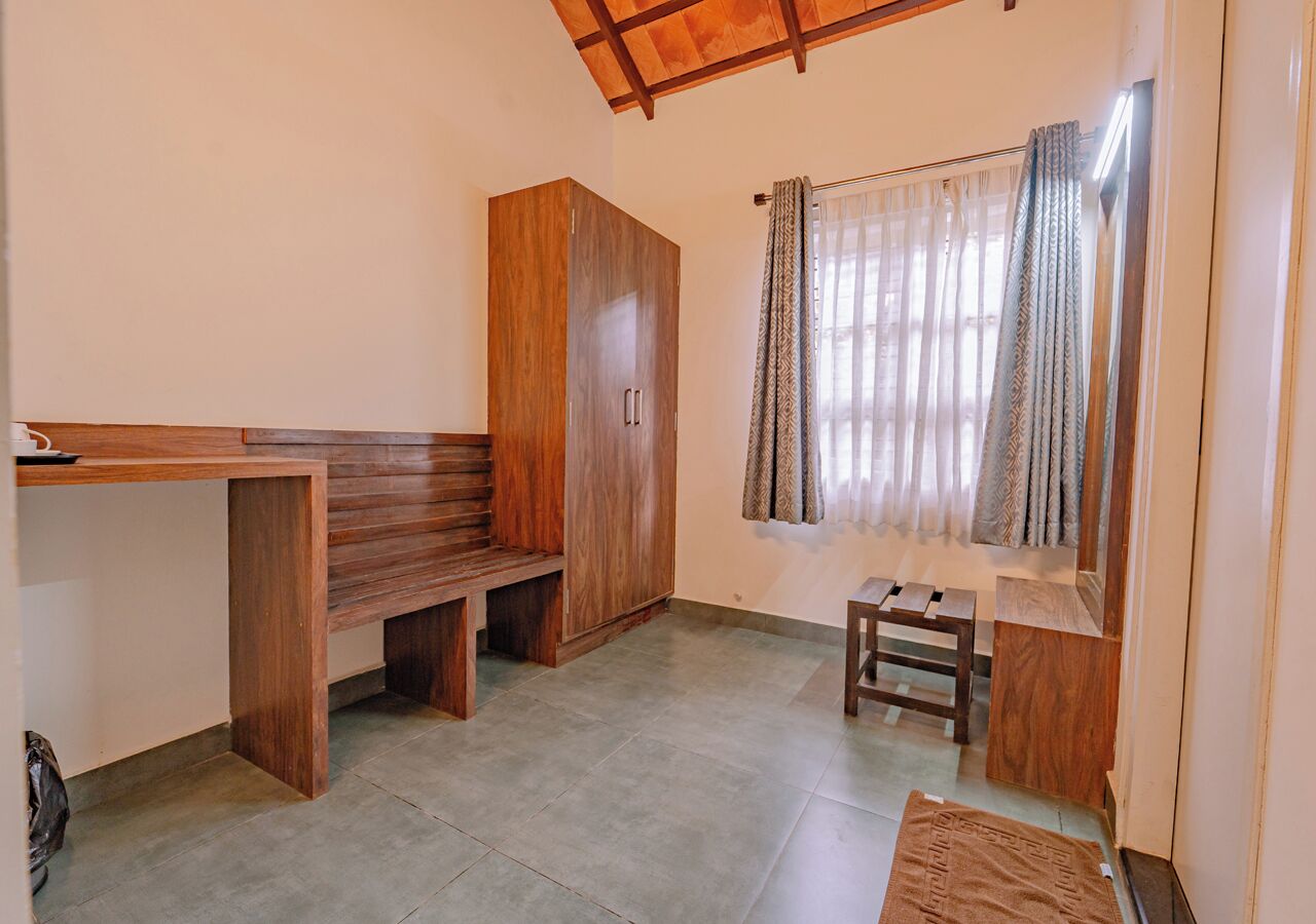 Una habitación con un banco de madera, un armario y una mesita.