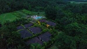 Un resort con varias edificaciones tipo bungaló dispuestas en un patrón de cuadrícula, rodeado de un bosque denso.