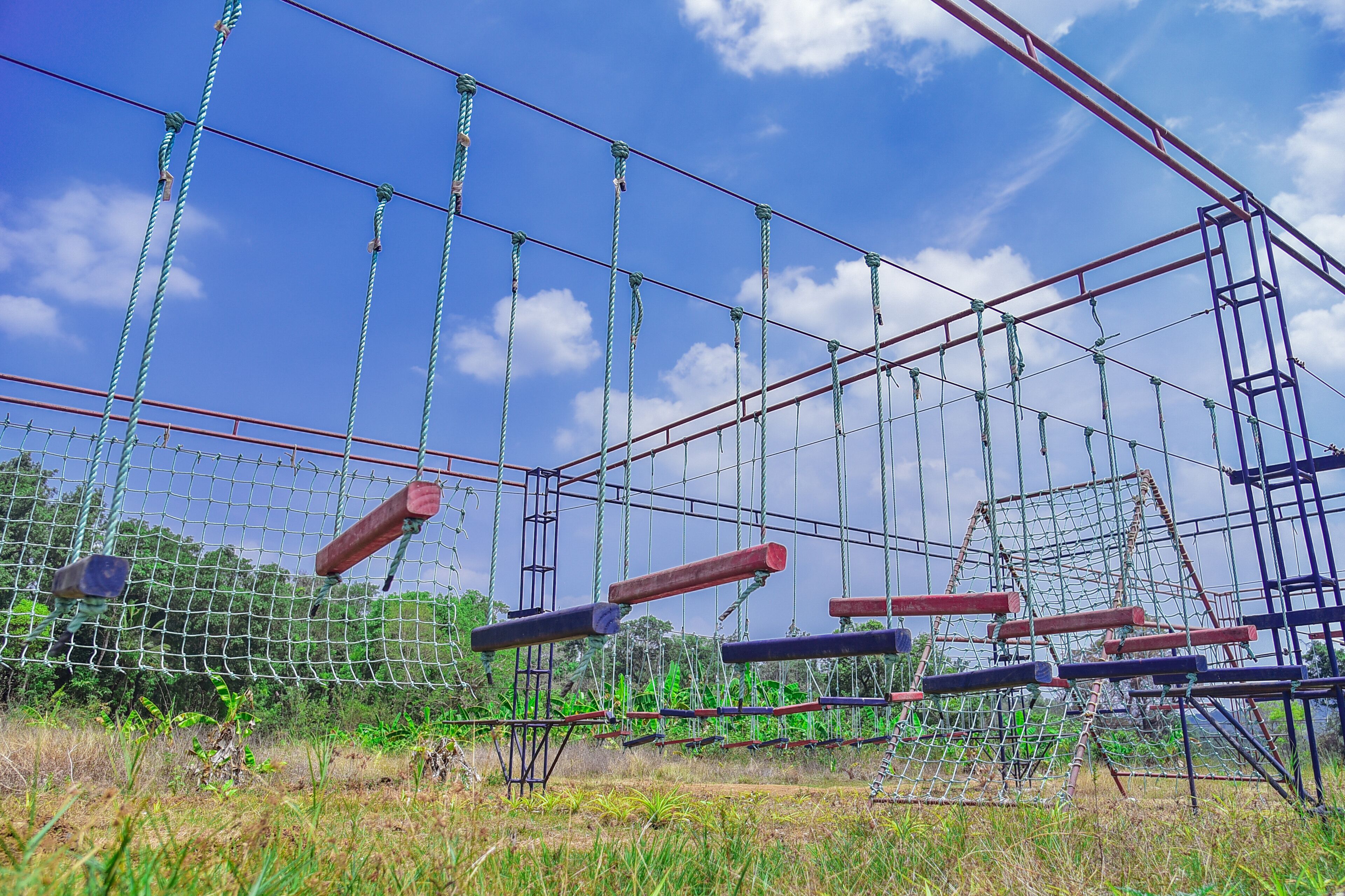 A rope bridge structure with suspended platforms and a netted enclosure.