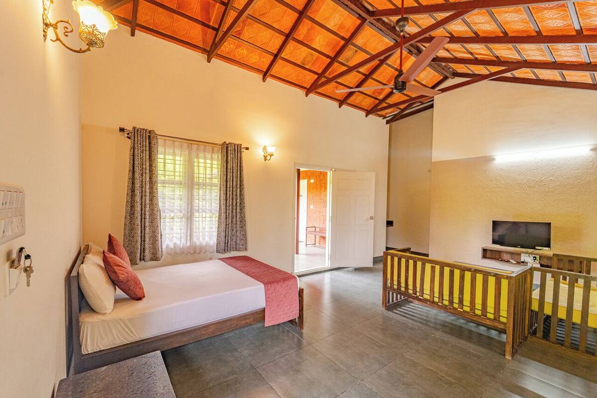 A bedroom with a bed, a TV, and a balcony.