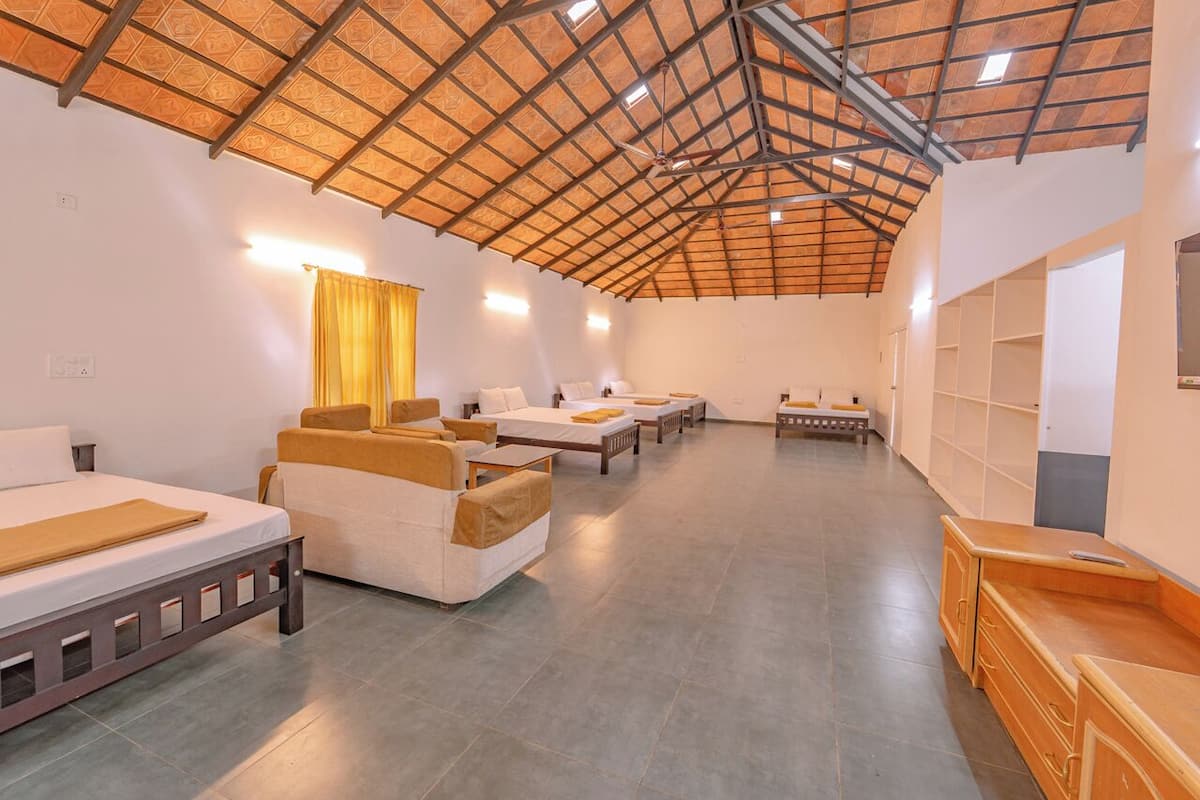 A spacious room with multiple beds, a wooden ceiling, and a tiled floor.