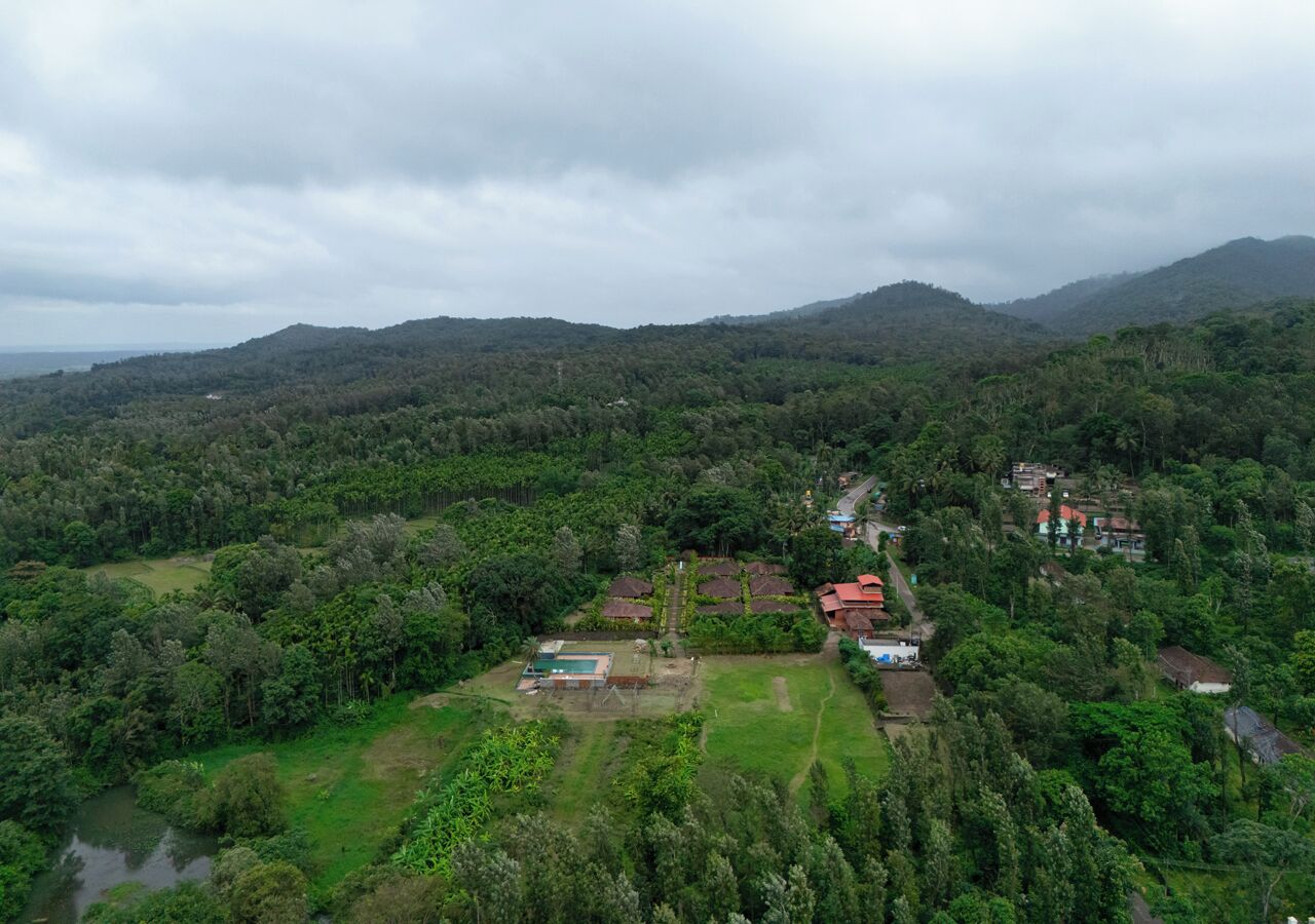 An aerial view of a rural area with scattered houses, a swimming pool, and a river.