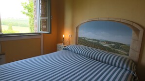 Un dormitorio con cama, una mesita de noche, una lámpara y un mural en la pared.