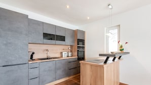 A modern kitchen with grey cabinets, a wooden countertop, and a built-in oven. - Chalet in Stuhlfelden Near Ski Slopes (Mittersill)