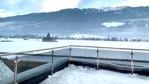 A snowy landscape with mountains in the background, a fenced area in the foreground, and a building partially obscured by snow. - Chalet in Stuhlfelden Near Ski Slopes (Mittersill)