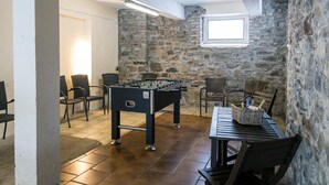 A room with a foosball table, stone walls, and a window.