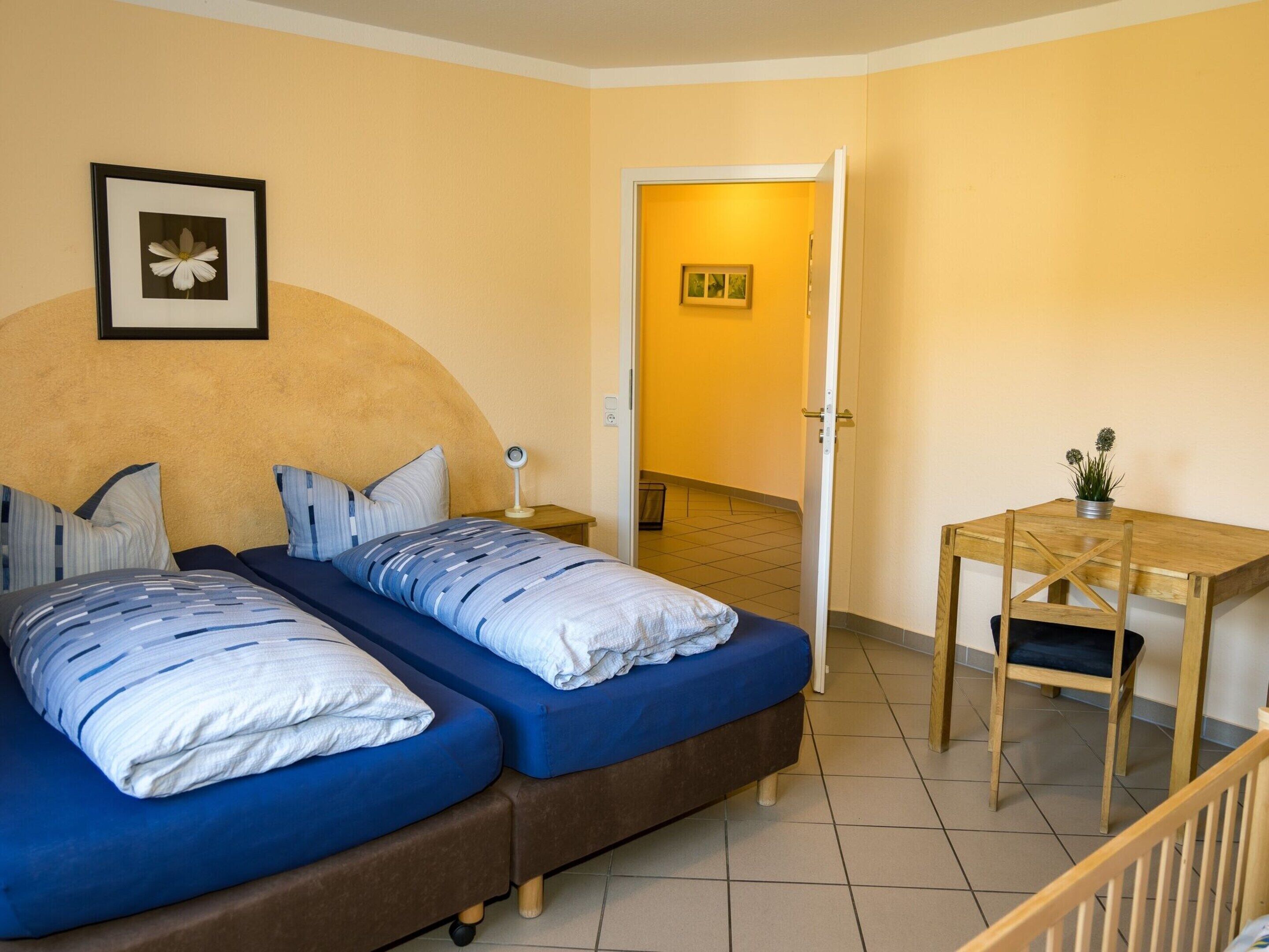 A room with two beds, a desk, and a chair.