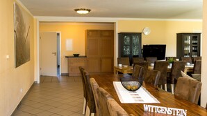 A dining area with a wooden table, brown upholstered chairs, and a nameplate reading "WITGENSTEIN".